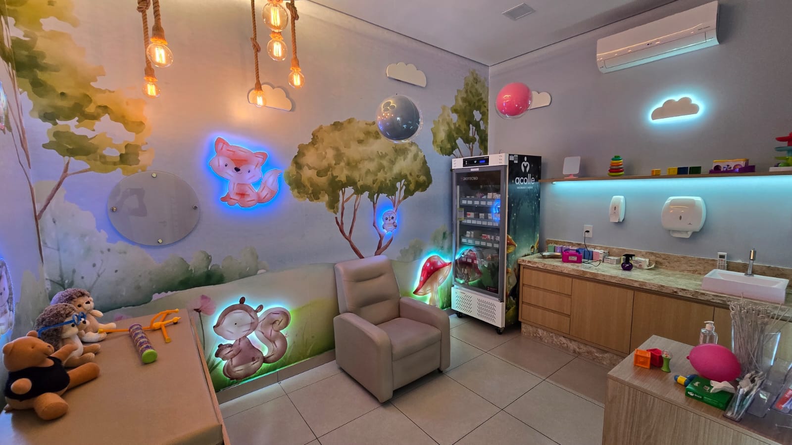 Sala de vacinação com câmara refrigerada Acolle, mural de árvores e poltrona reclinável confortável